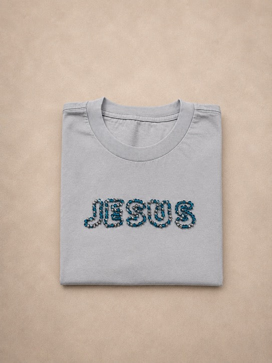 Folded oversized Powder Blue t-shirt with hand-beaded JESUS lettering