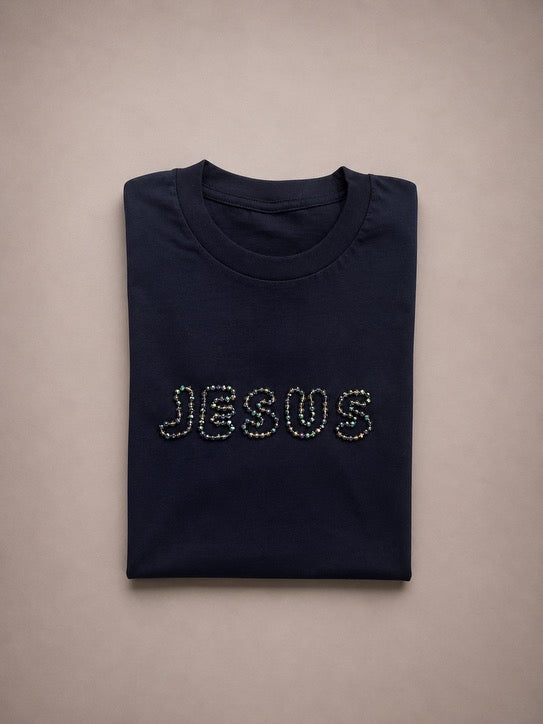 Folded Navy Blue t-shirt with hand-beaded JESUS lettering